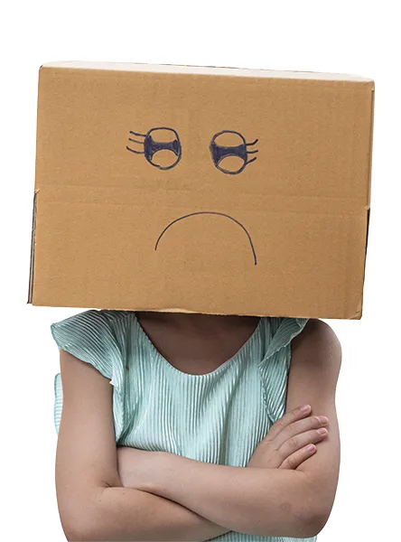 Kleines Mädchen trägt Pappkarton auf dem Kopf mit unglücklichem Gesicht